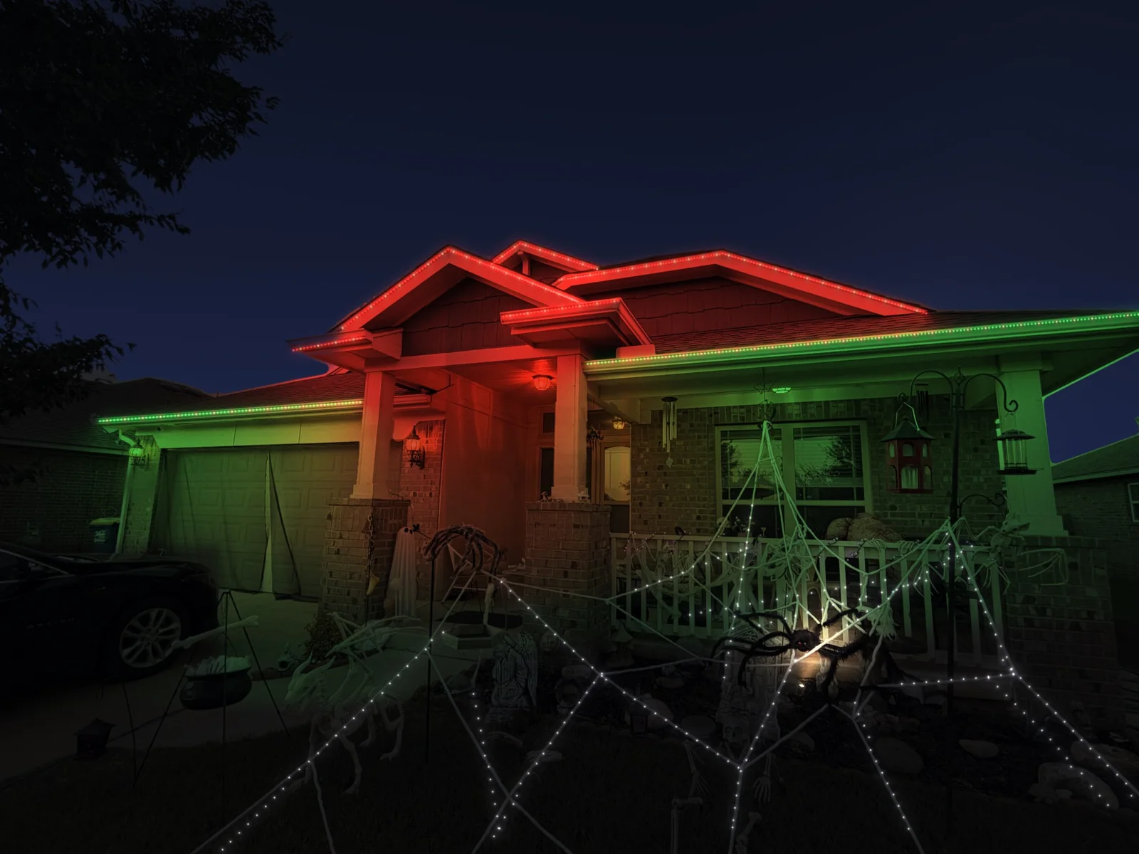 Mockup of a brick home at night with its roofline lit in red and green with warm white