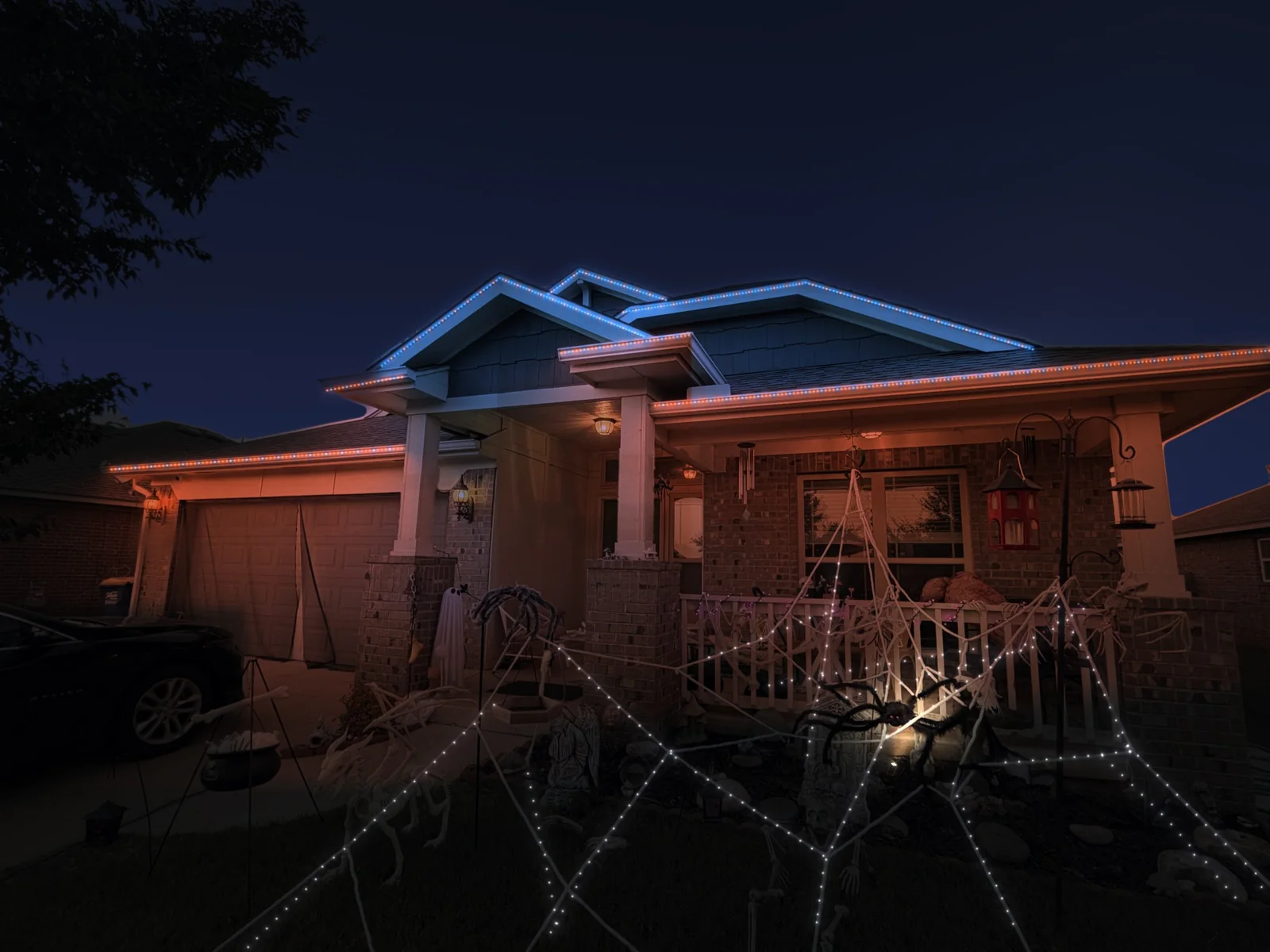 Mockup of a brick home at night with its roofline lit in blue and orange